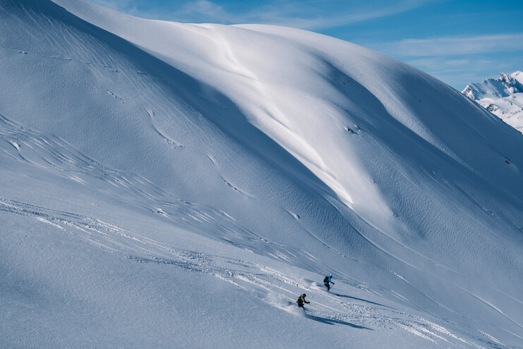 Tief verschneite Hänge am Arlberg Gruppe von Freeridern bei der Abfahrt